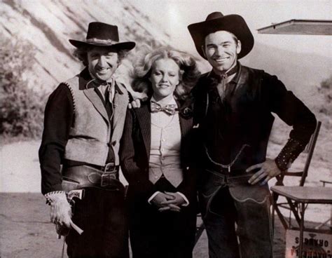 an old black and white photo of two men and a woman in cowboy hats standing next to each other