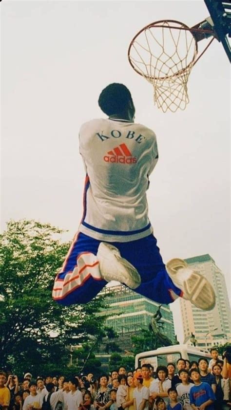 a man jumping up into the air to dunk a basketball in front of a crowd