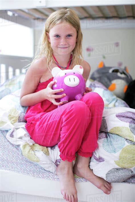 Portrait of girl sitting on bunk bed holding piggy bank - Stock Photo ...