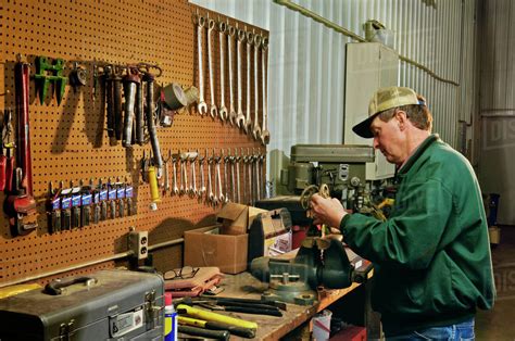 Agriculture - A farmer works on machinery in his farm workshop / Iowa, USA. - Stock Photo - Dissolve