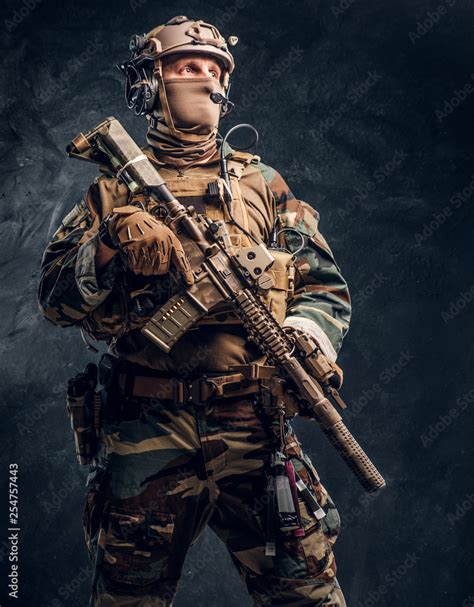 Special forces soldier in military uniform posing with assault rifle. Studio photo against a ...