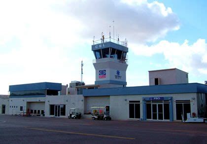 an airport building with a control tower in the background and cars ...