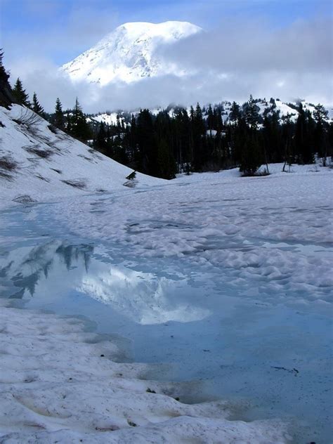 the snow covered mountains are reflected in the still water on the ...