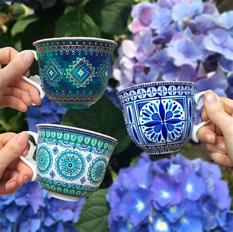 three people holding coffee cups in front of blue flowers