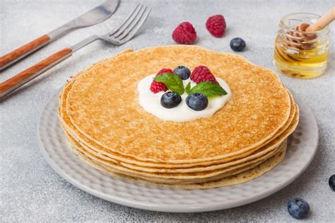 Premium Photo | Plate of delicious thin pancakes with berries on grey table