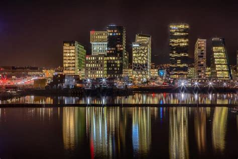 the city is lit up at night and reflecting in the water