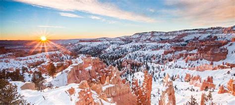 the sun shines brightly in the sky over snow covered canyons and trees ...