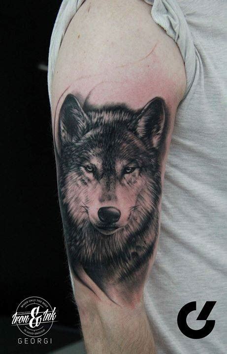 Black and grey wolf tattoo on the right upper arm (in