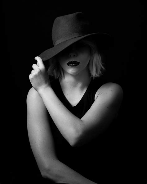 black and white photograph of a woman wearing a hat with her hands on ...