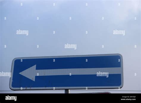 Directional arrow on a blue background pointing left Stock Photo - Alamy