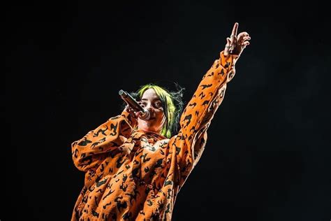 a woman with green hair wearing an orange outfit and holding a microphone in her hand