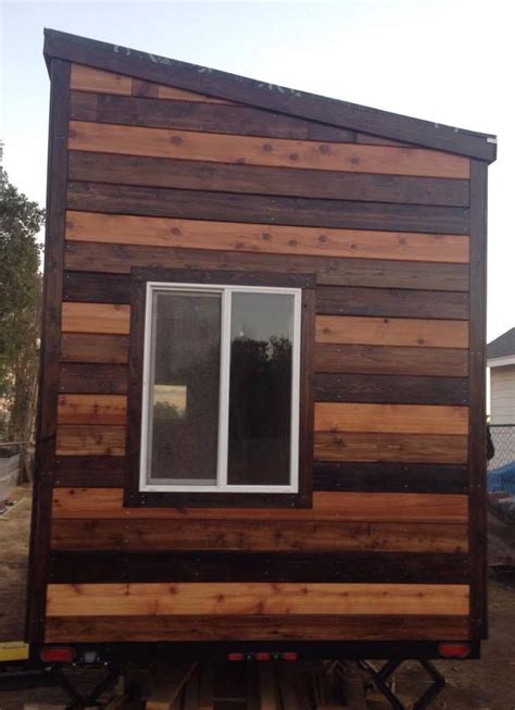 the tiny house is made out of wood and has windows on each side, along ...