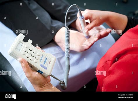 Foot pulse test in diabetic patient. Nurse using a portable Doppler ultrasound device to check ...