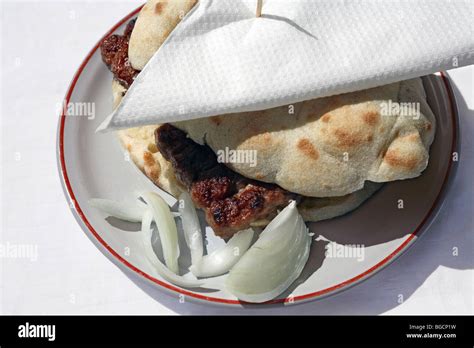 Cevapcici in bread with sliced onion served on a plate. Bosnia, Bosnian ...