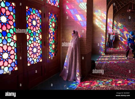 A Tourist stands in the light coming through the stain glass windows of ...