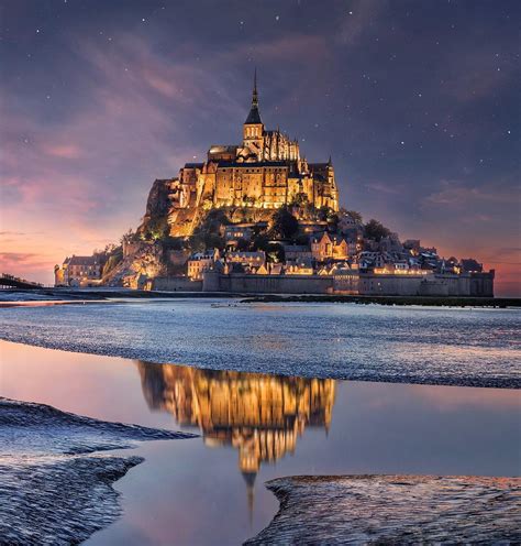 A night-lit Mont Saint Michel reflecting off the low tide : r/MostBeautiful