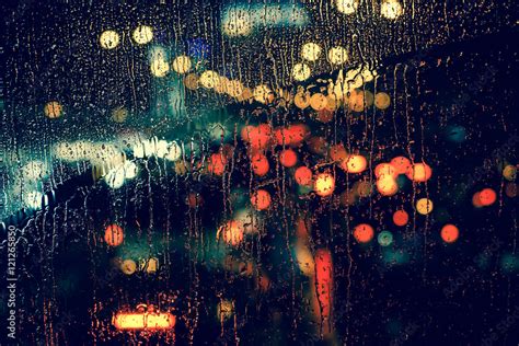 City view through a window on a rainy night,Rain drops on window with ...