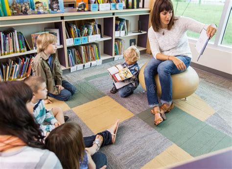 Teacher Reading Book To Children in Library Stock Photo - Image of holding, mother: 36549218