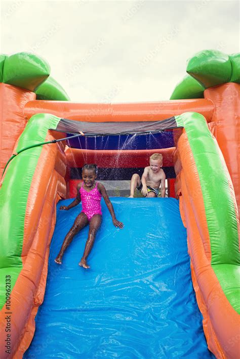 Happy smiling children playing on an inflatable slide bounce house Stock Photo | Adobe Stock