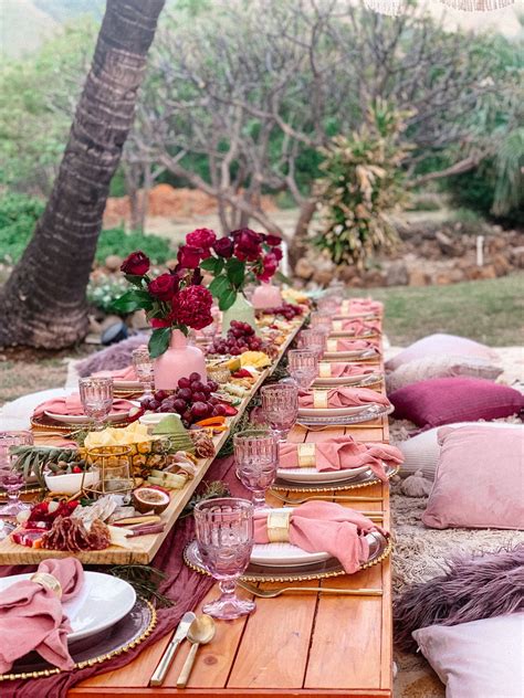 a long table set up with plates and place settings for an outdoor dinner in the woods