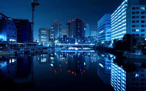 the city is lit up at night and reflecting in the water