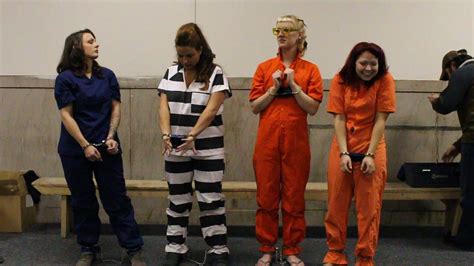 Four woman in different inmate suits get used to handcuffs and shackles ...