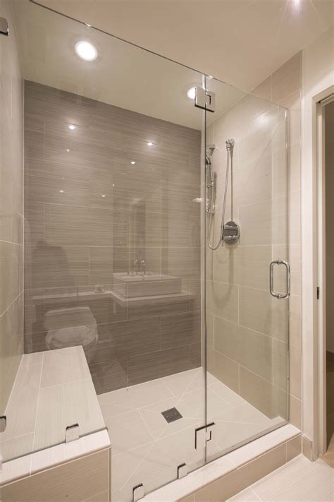 This modern bathroom has a large glass-enclosed shower in tile. The shower stall includes a ...