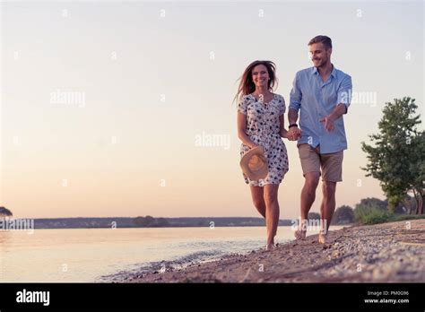 Couple walking on the beach at sunset Stock Photo - Alamy