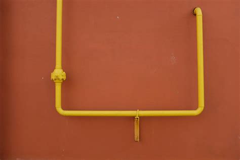 Yellow metal pipe on red wall · Free Stock Photo