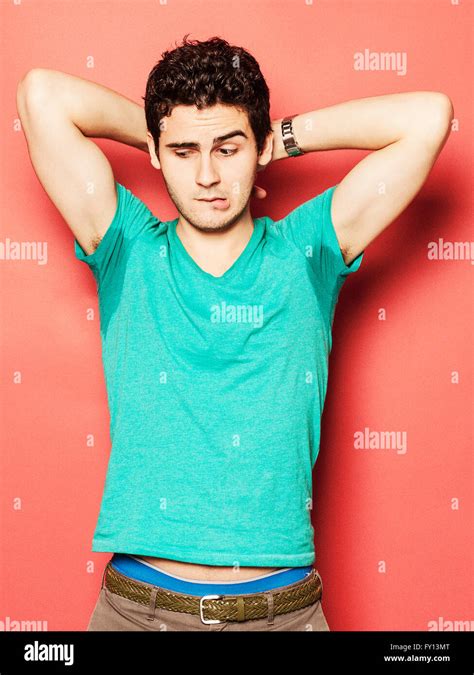 Young man biting lip while looking at sweaty armpit against red background Stock Photo - Alamy