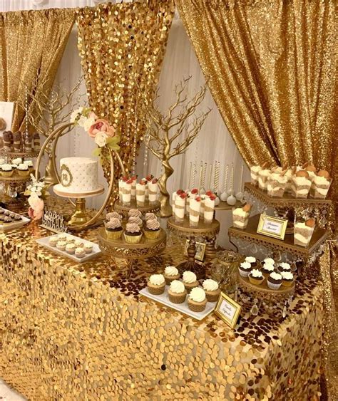 a table topped with cakes and cupcakes covered in gold sequined paper