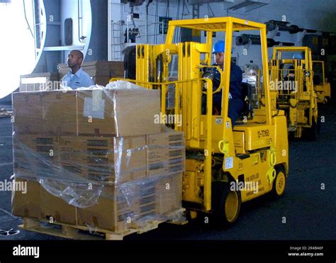 US Navy Store Keeper 3rd Class uses a forklift to transport bedding ...