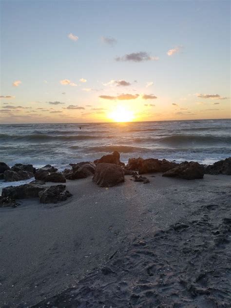 the sun is setting over the ocean and rocks