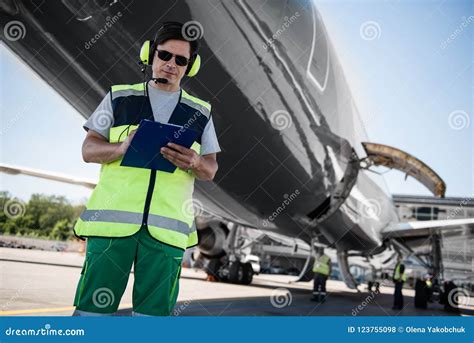 Airport Worker Filling Out Documents while Ground Crew Members Checking Plane before the Flight ...