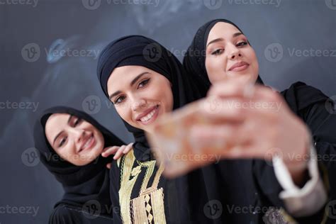 muslim women taking selfie picture in front of black chalkboard ...