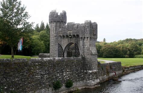 an old castle sitting on the side of a river next to a lush green field