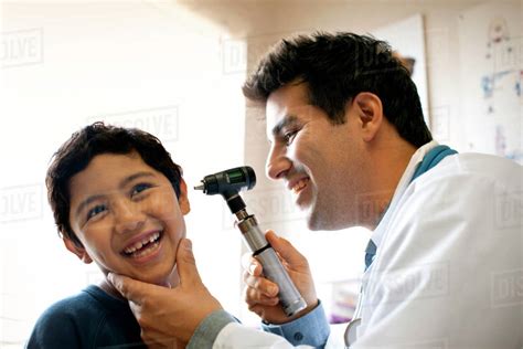 Doctor examining his young patient's ear with otoscope. - Stock Photo ...