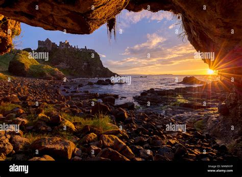 Sunset over Dunluce Castle from inside a sea cave. Causeway Coast ...