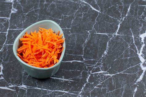 Free Photo | Grated fresh carrot in a blue ceramic bowl.