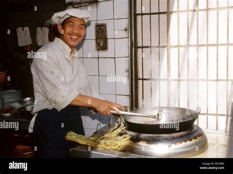 A smiling local man cooking with large wok outside a restaurant,Kunming,Yunnan Province,China ...