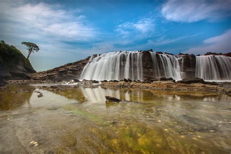 Waterfalls Near Hills Under Blue Sky and White Clouds · Free Stock Photo