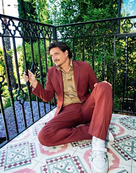 a man sitting on top of a tiled floor next to a metal railing holding a cell phone