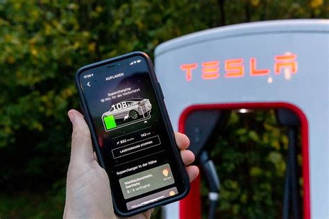Tesla supercharging in the smartphone app held in front a Tesla charging station - Creative ...