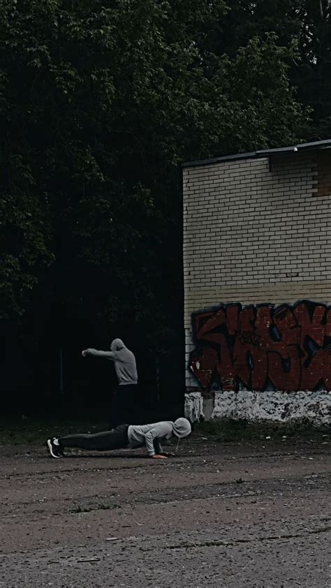 a person laying on the ground in front of a building with graffiti written on it