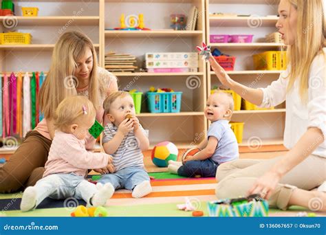 Group of Babies in Nursery. Nursery Teacher and Assistant Play with Kids Stock Image - Image of ...