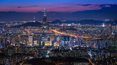 an aerial view of the city at night with lights and skyscrapers in the foreground