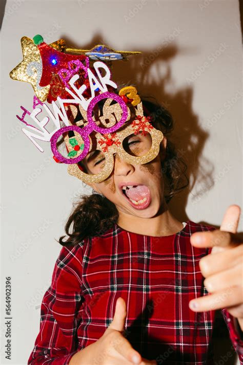 Kid making funny faces wearing Happy 2023 glittery party accessories Stock Photo | Adobe Stock