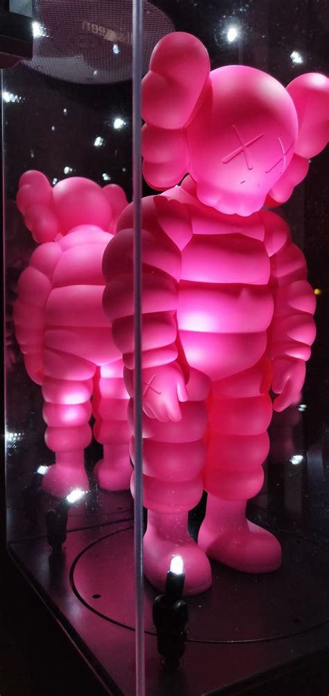 a large pink teddy bear sitting on top of a black table next to a glass ...