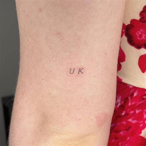 "UK" lettering tattoo located on the tricep.