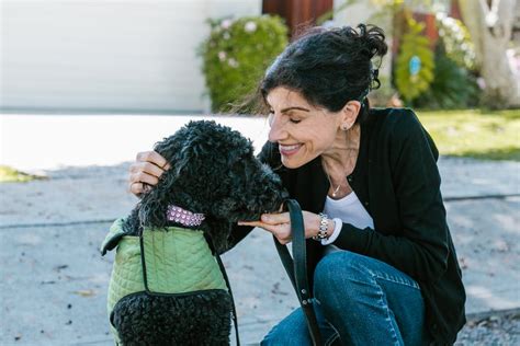 Woman in Black Cardigan Holding Black Curly Coated Dog · Free Stock Photo